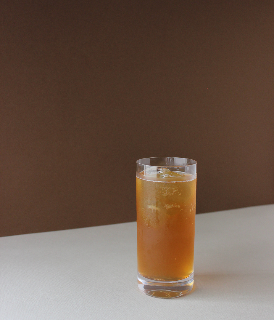 A glass of iced tea on a table with a brown background.