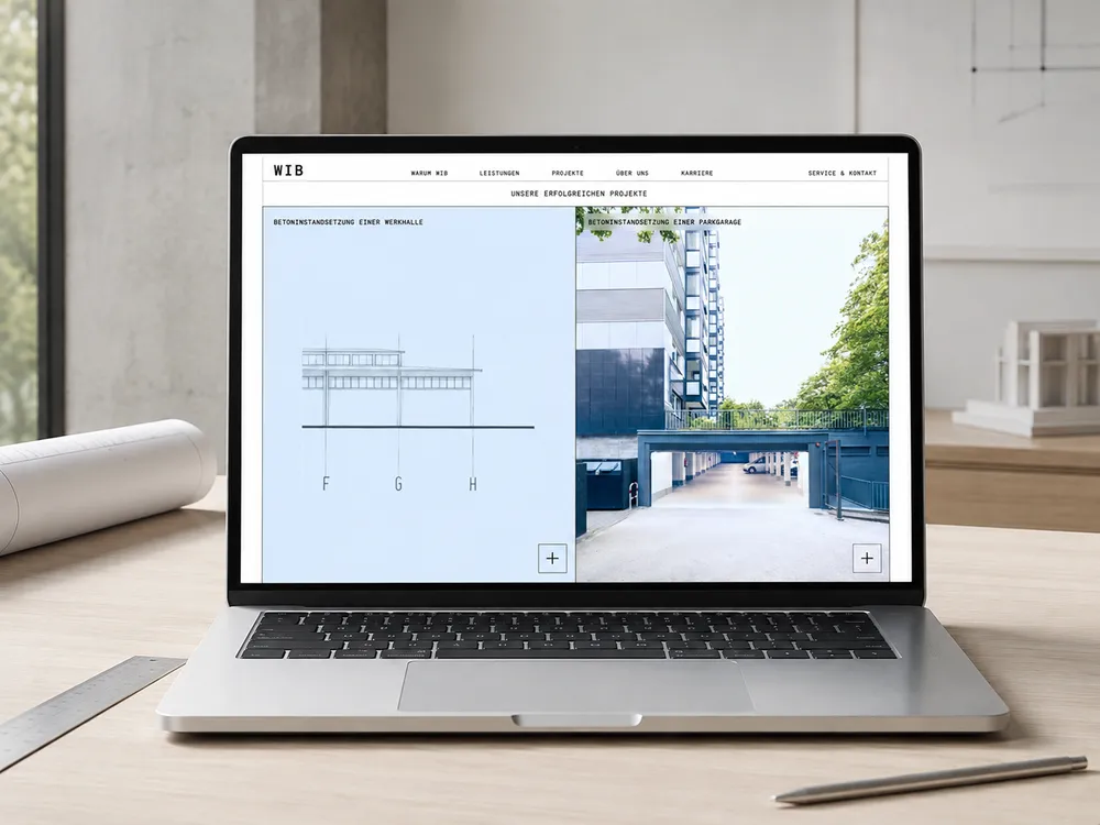 A laptop displaying architectural design software with a technical drawing on the left and a photo of a building exterior on the right. The workspace includes a rolled-up paper, a ruler, and a pencil on a wooden desk.