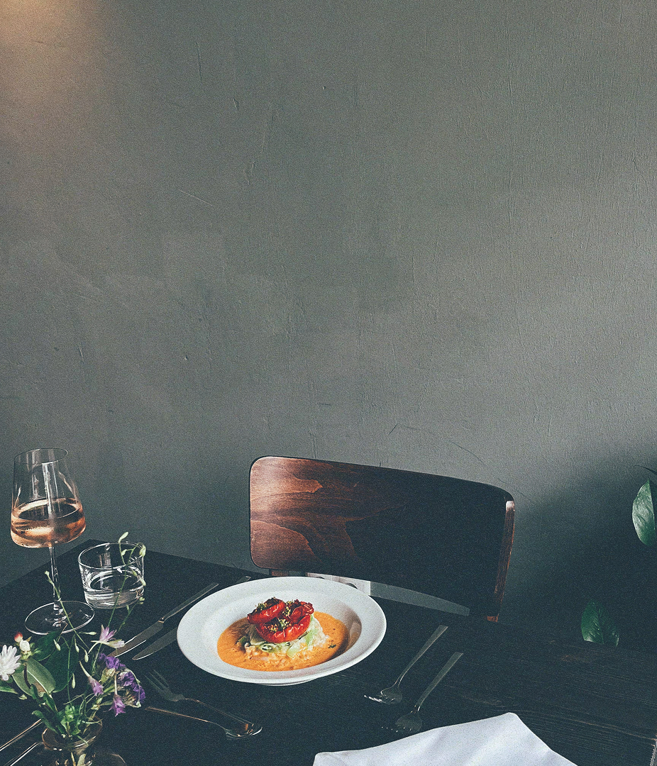 A plate of gourmet food on a table with a glass of wine.