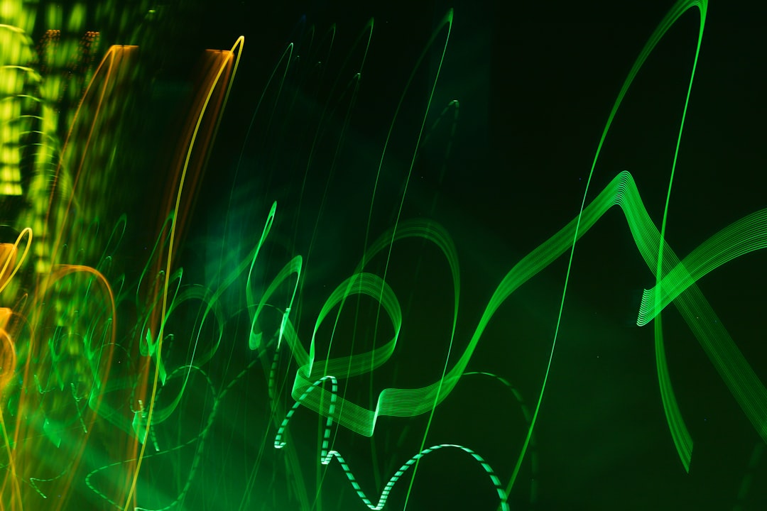 Abstract light trails in green and orange on a dark background.