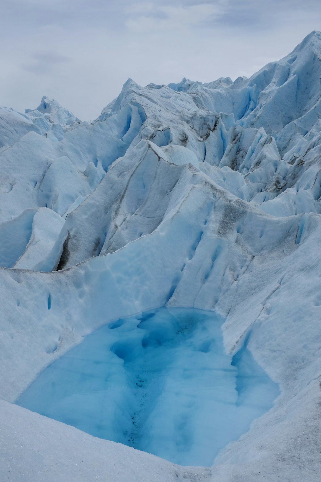 Blue glacial ice with a small meltwater pool.