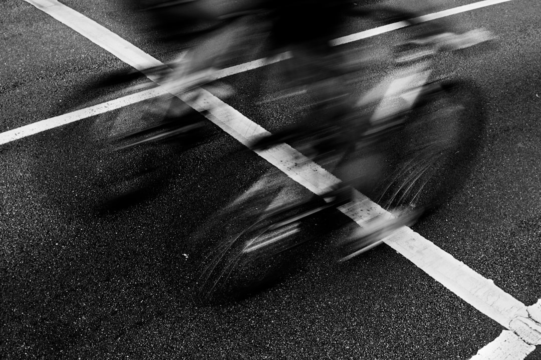 Blurred motion of cyclists crossing a street intersection.