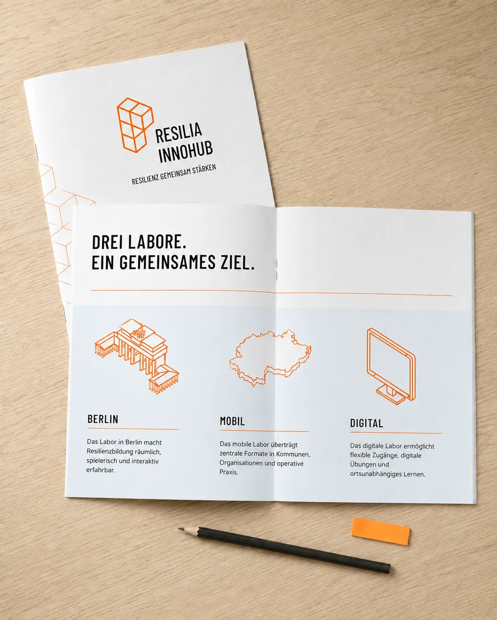 Brochure on a table titled 'Resilia Innohub' with sections for Berlin, Mobile, and Digital initiatives.