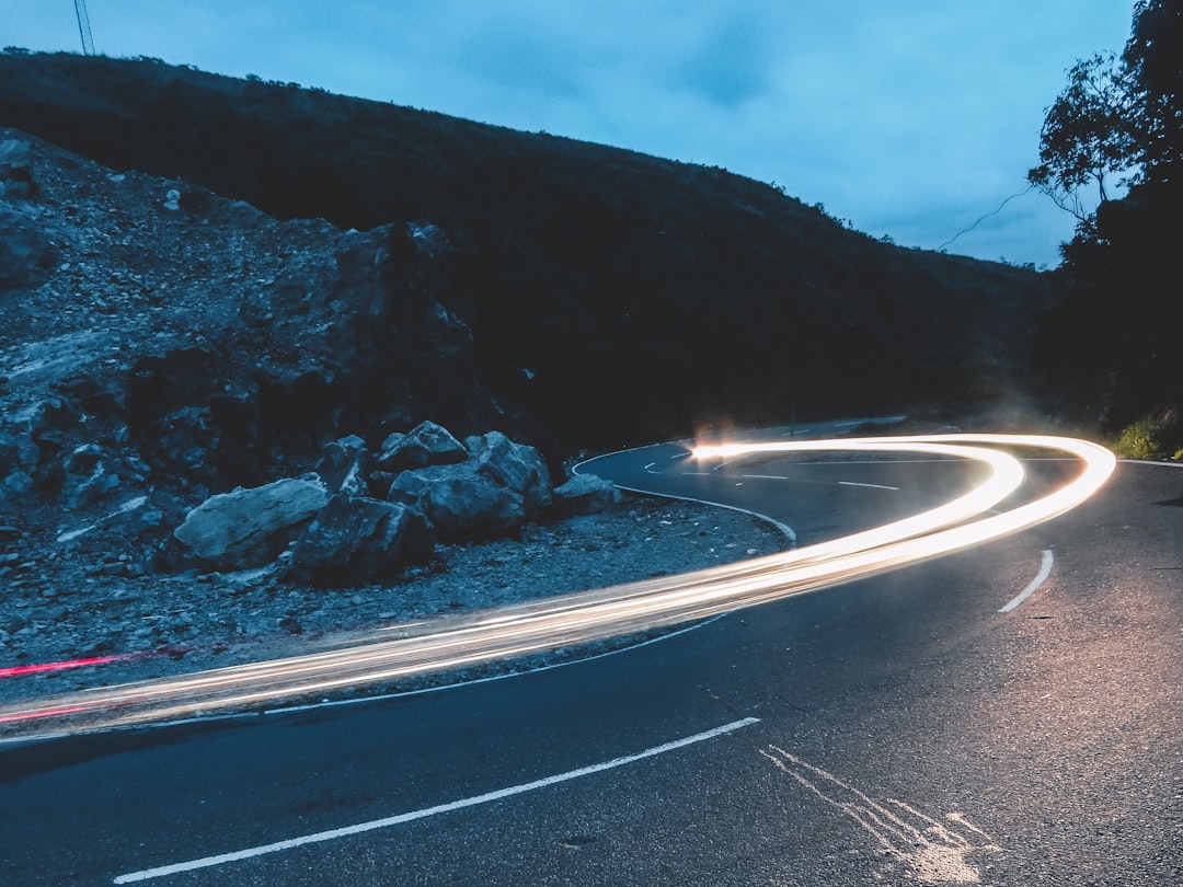 Car light trails on a winding mountain road at dusk.