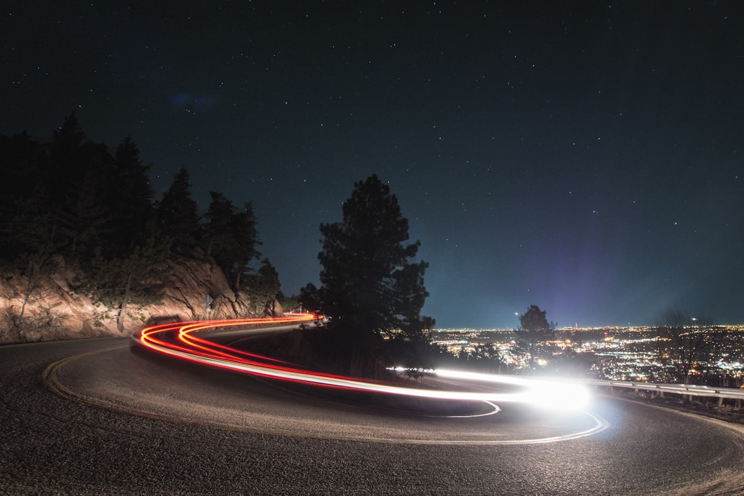 Car light trails on a winding mountain road at night.