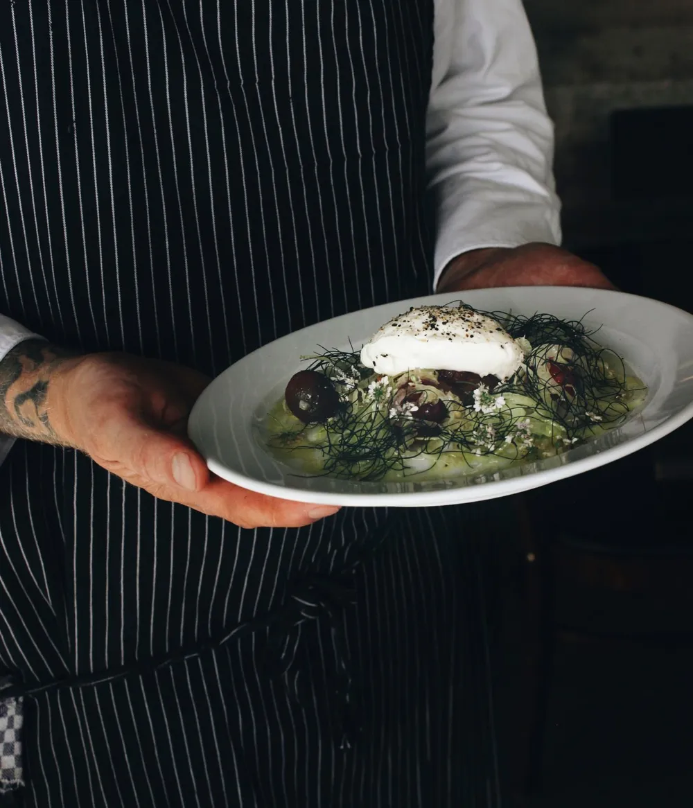 Chef holding a plated gourmet dish.