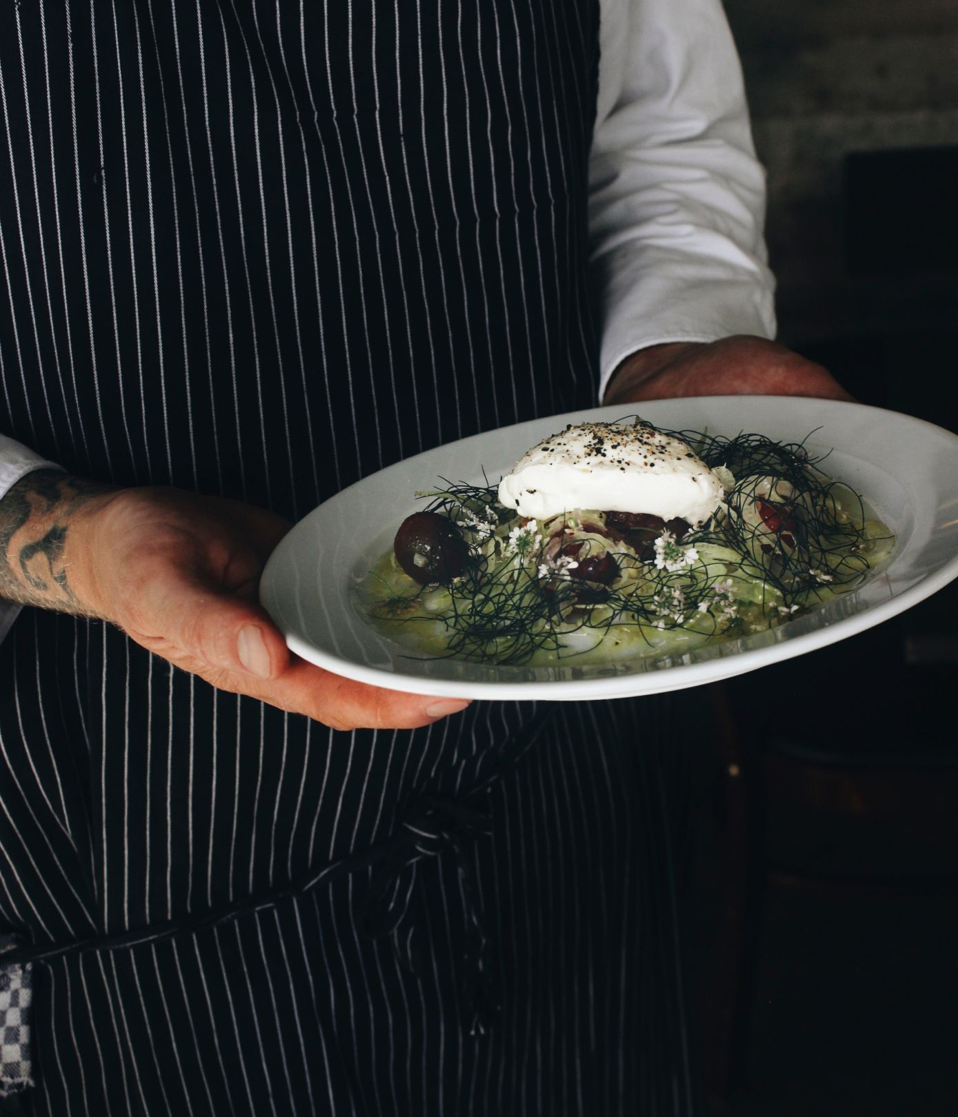 Chef holding a plated gourmet dish.