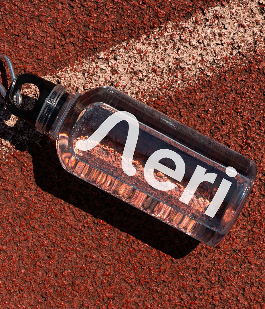 Clear water bottle with 'Aeri' logo on a textured red surface.