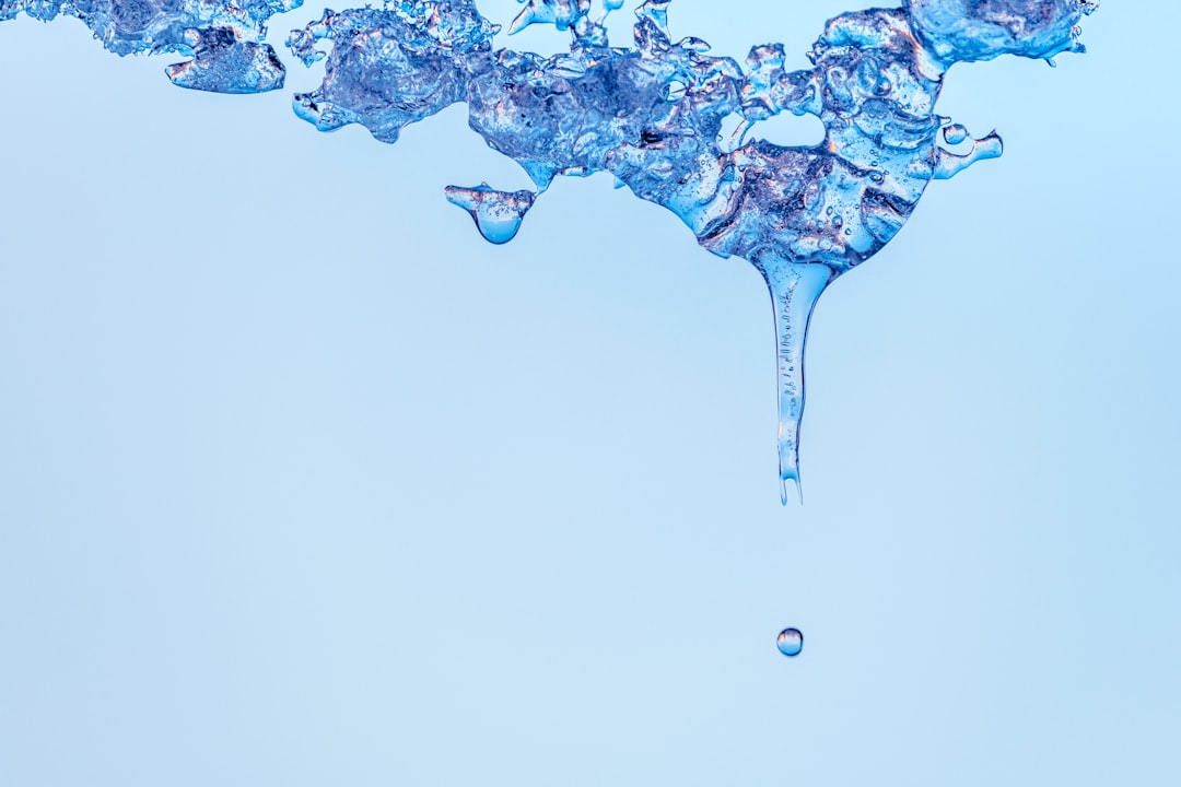 Close-up of melting ice with a droplet falling.