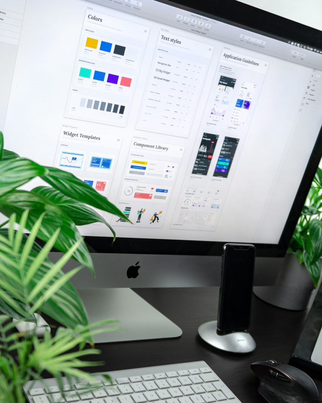 Computer monitor displaying a design interface with plants nearby.