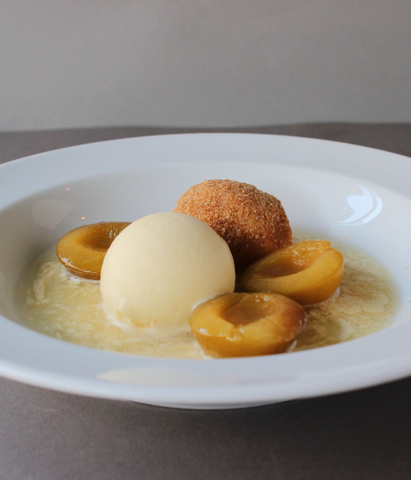 Dessert with ice cream, fruit, and a pastry on a plate.