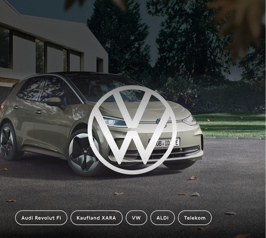 Ein modernes Auto in einer urbanen Umgebung, möglicherweise ein Elektrofahrzeug, mit einem großen VW-Logo im Vordergrund. Hintergrund zeigt Bäume und ein modernes Gebäude. Unten sind mehrere Markenoptionen, darunter Audi und VW, in Kreisform.