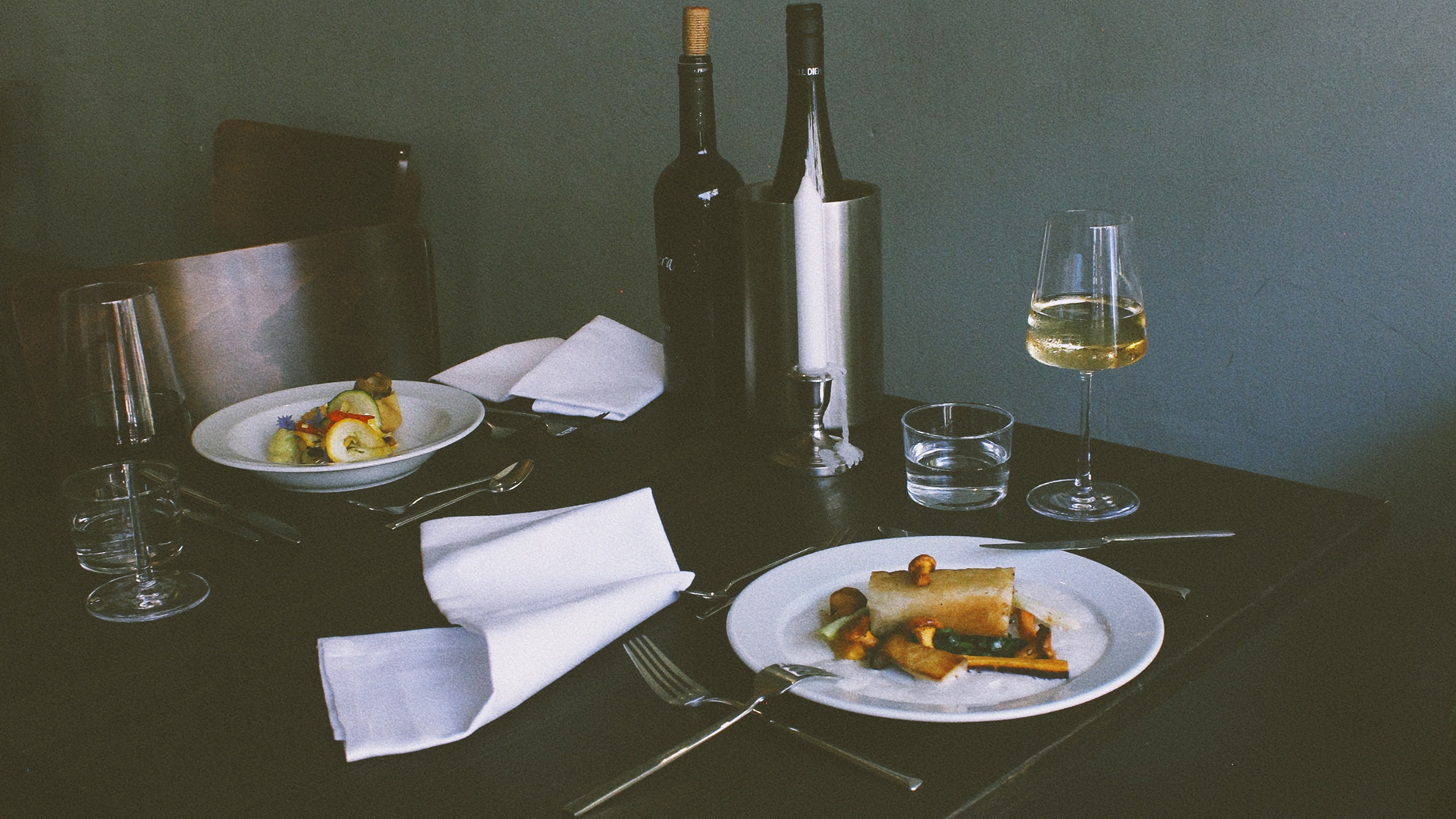 Elegant dining table with plates of gourmet food and wine glasses.