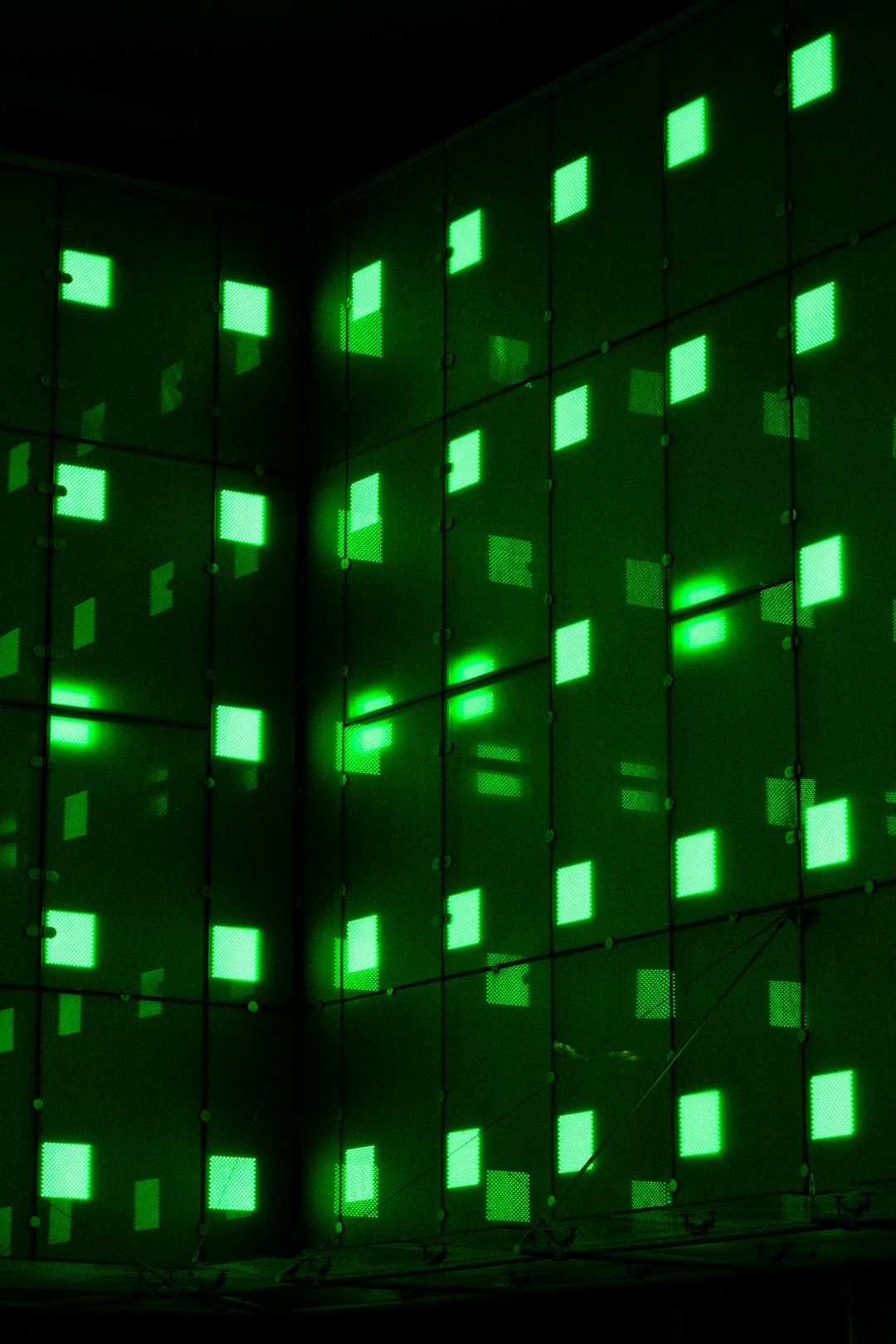 Green illuminated wall with square patterns.