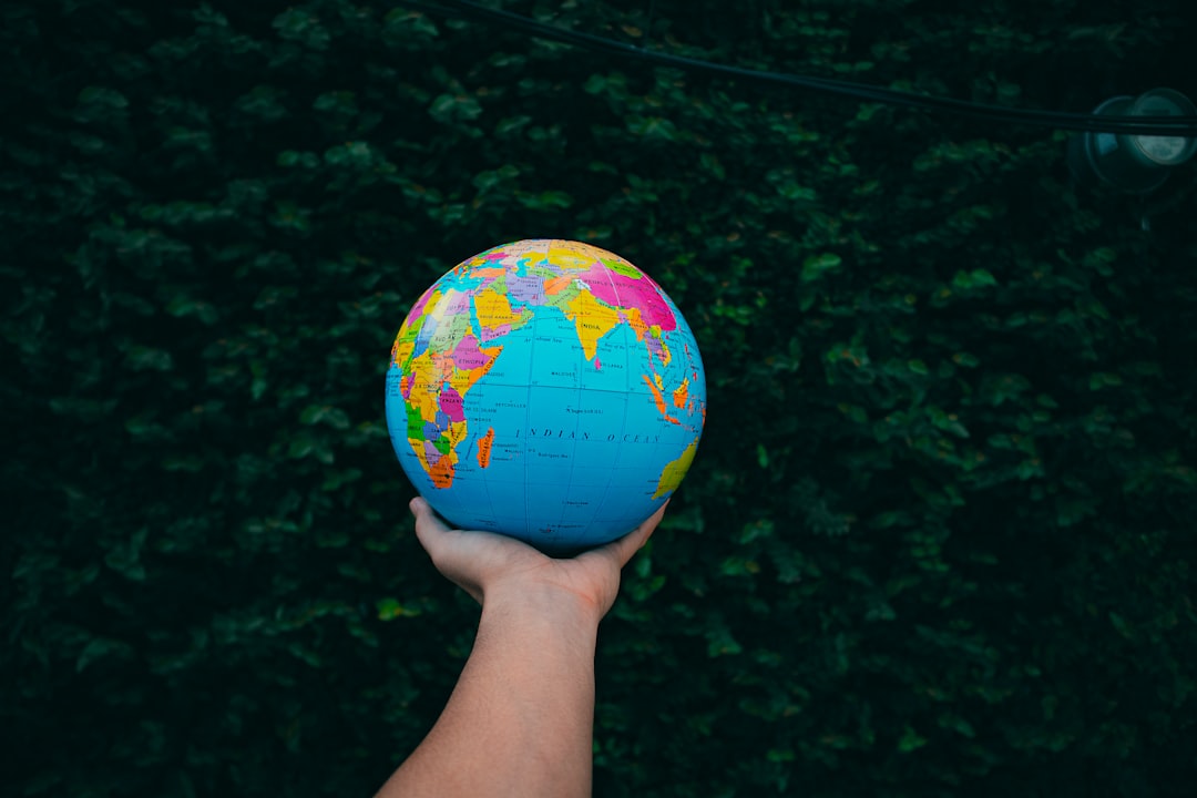 Hand holding a globe against a leafy background.