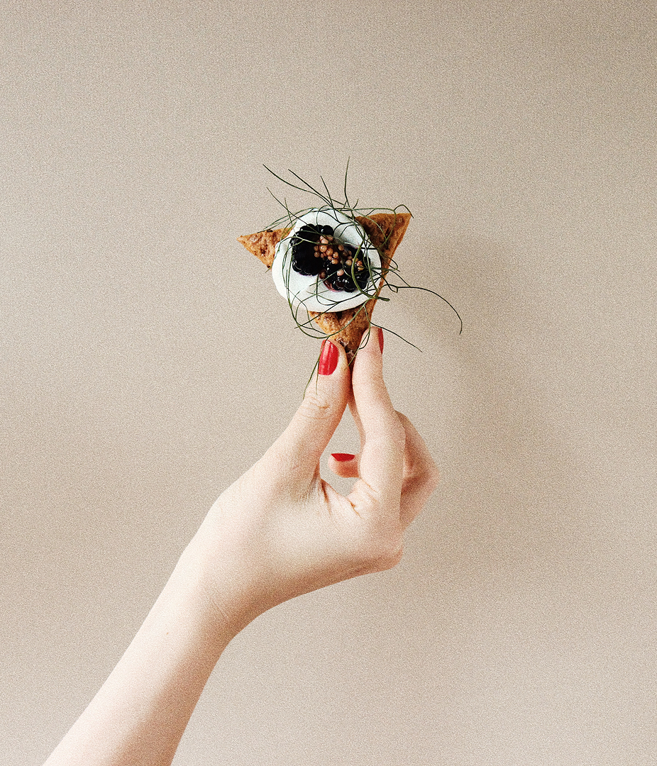 Hand holding a small appetizer with garnish.
