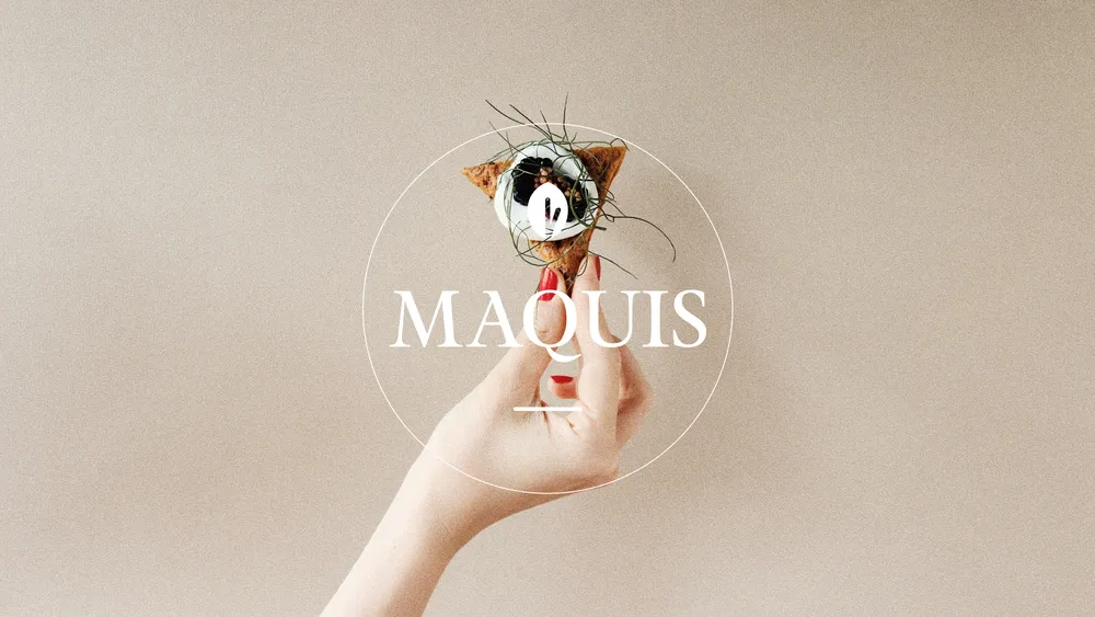 Hand holding a small appetizer with the word 'MAQUIS' overlaid.