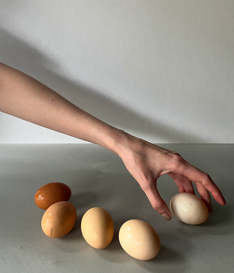 Hand reaching for an egg on a table.