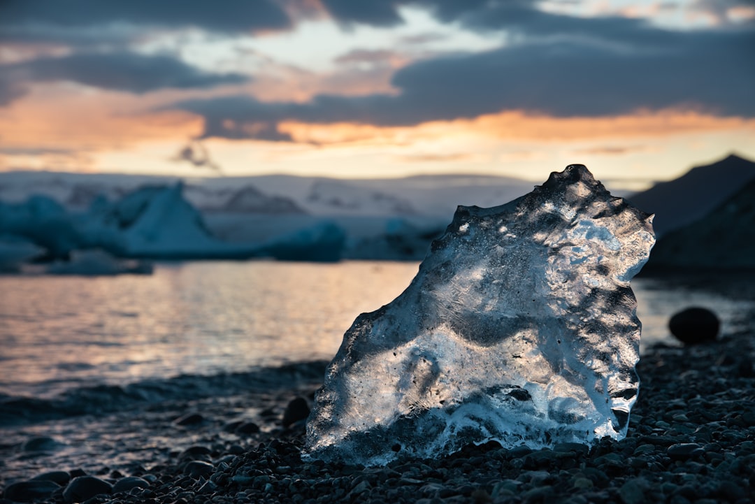 Ice chunk on a rocky shore at sunset.