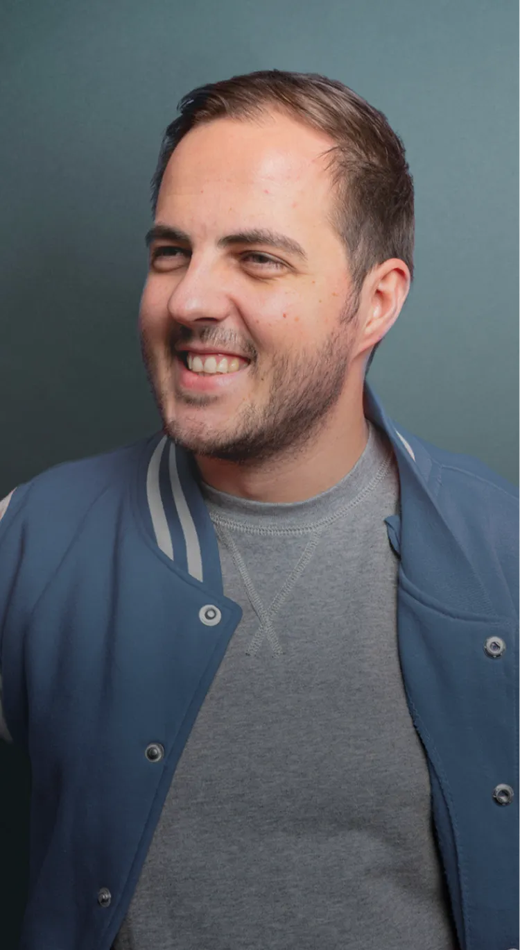 Smiling man in a blue-gray jacket against a gray background