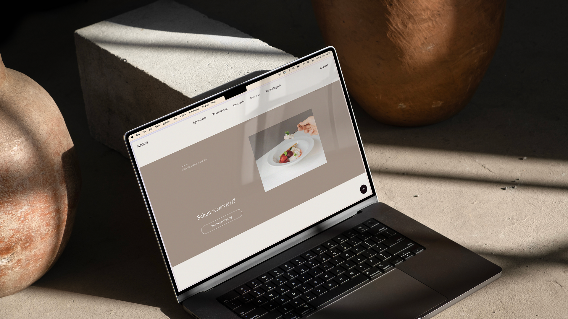 Laptop displaying a restaurant website on a concrete floor.