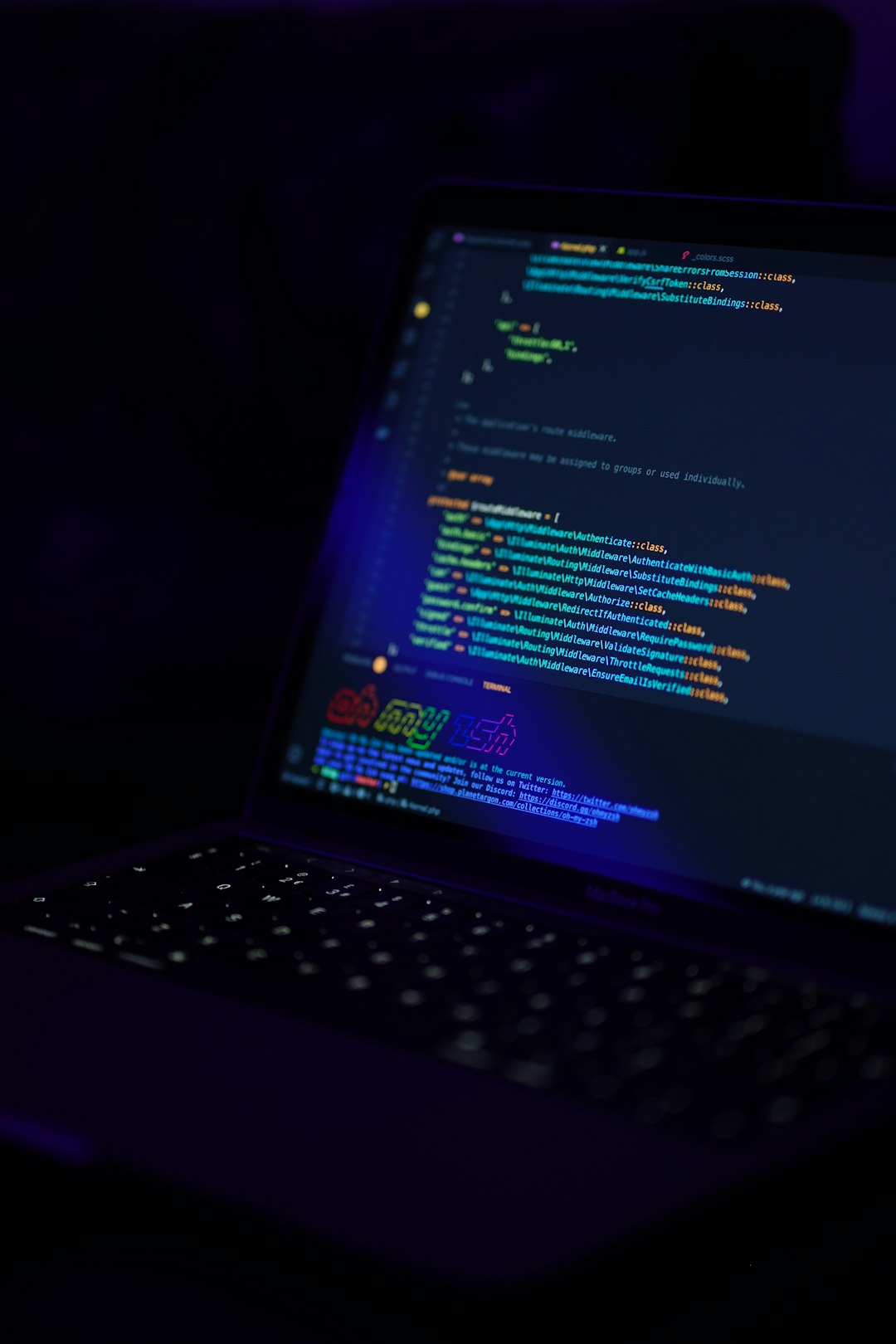 Laptop displaying colorful code on screen in a dark setting.
