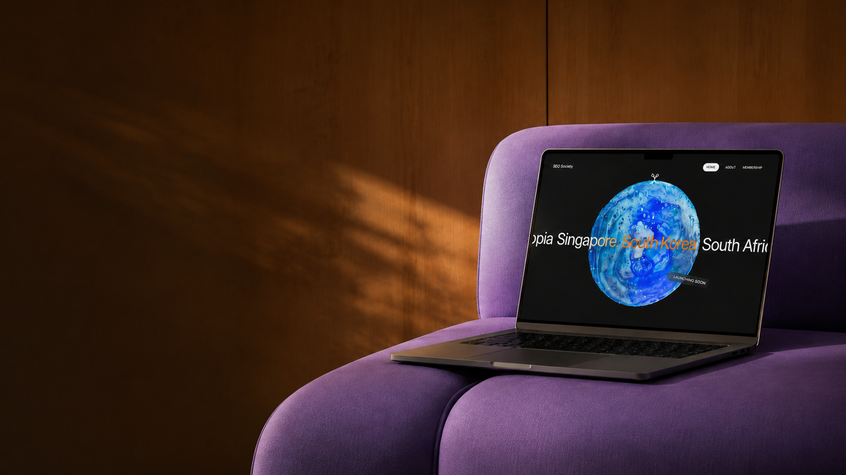 Laptop displaying 'SEO Society' on a purple chair.