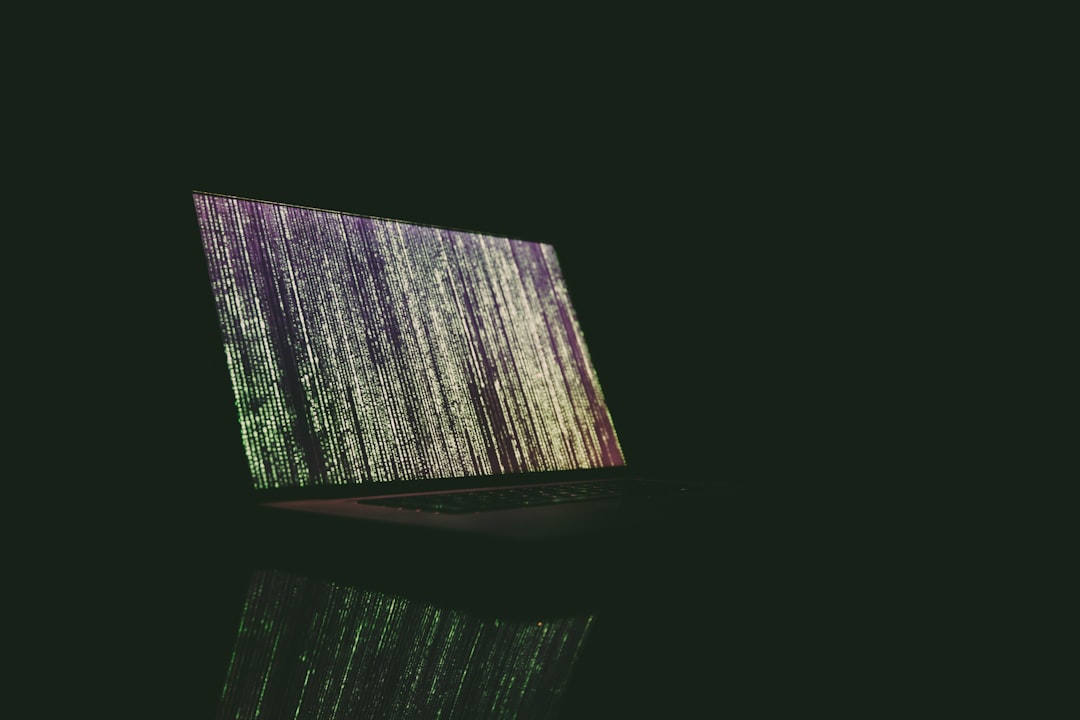 Laptop displaying vertical lines of code in a dark setting.