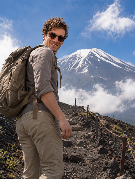 Man hiking on a mountain trail with a snowy peak in the background.