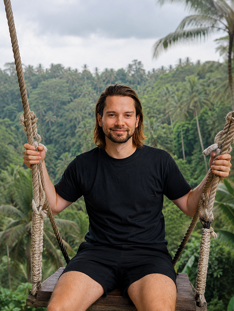 Man sitting on a swing in a tropical forest.