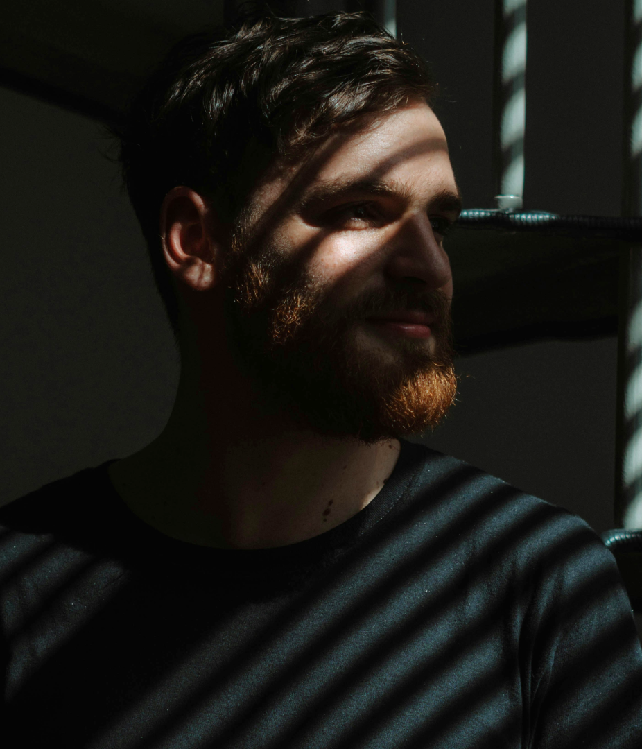 Man with a beard in shadowed lighting.