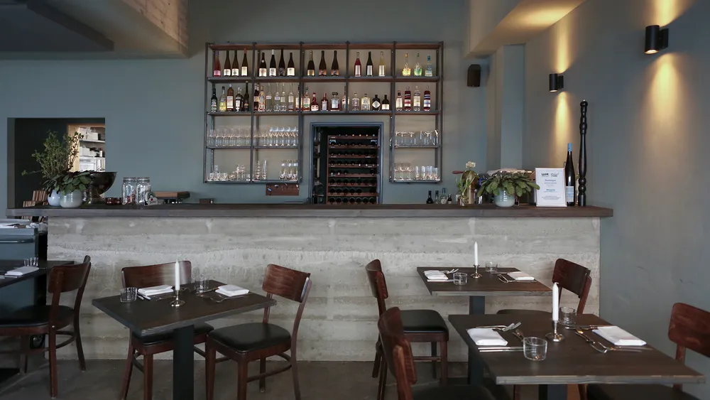 Modern restaurant interior with a bar and dining tables.
