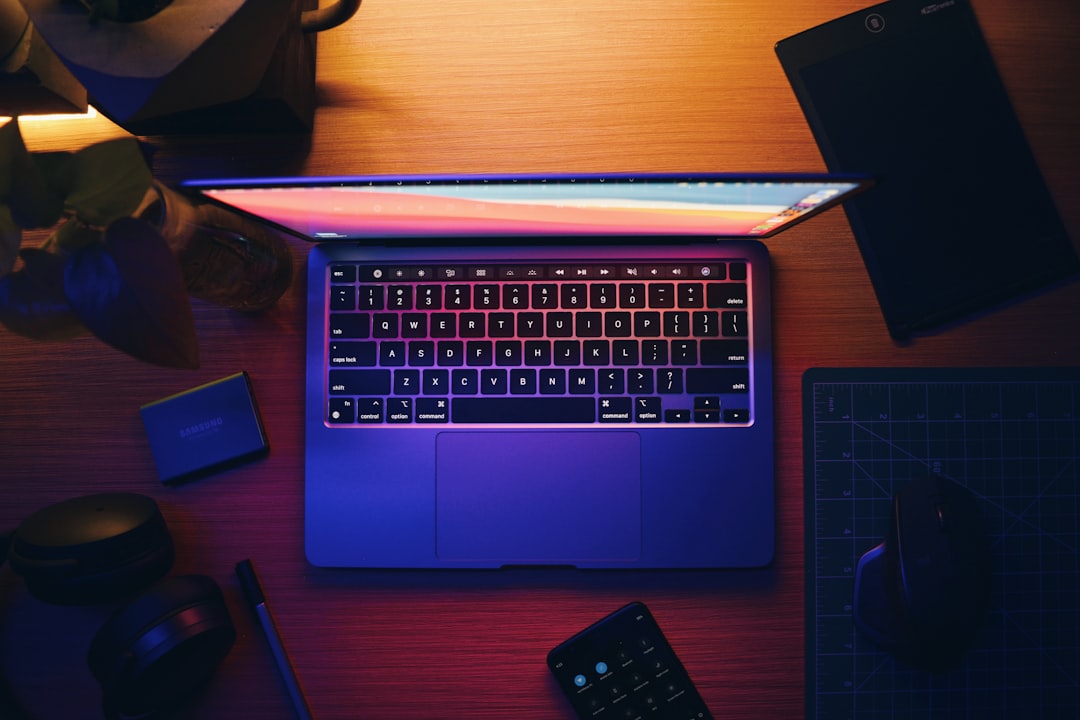 Open laptop on a wooden desk with colorful lighting.