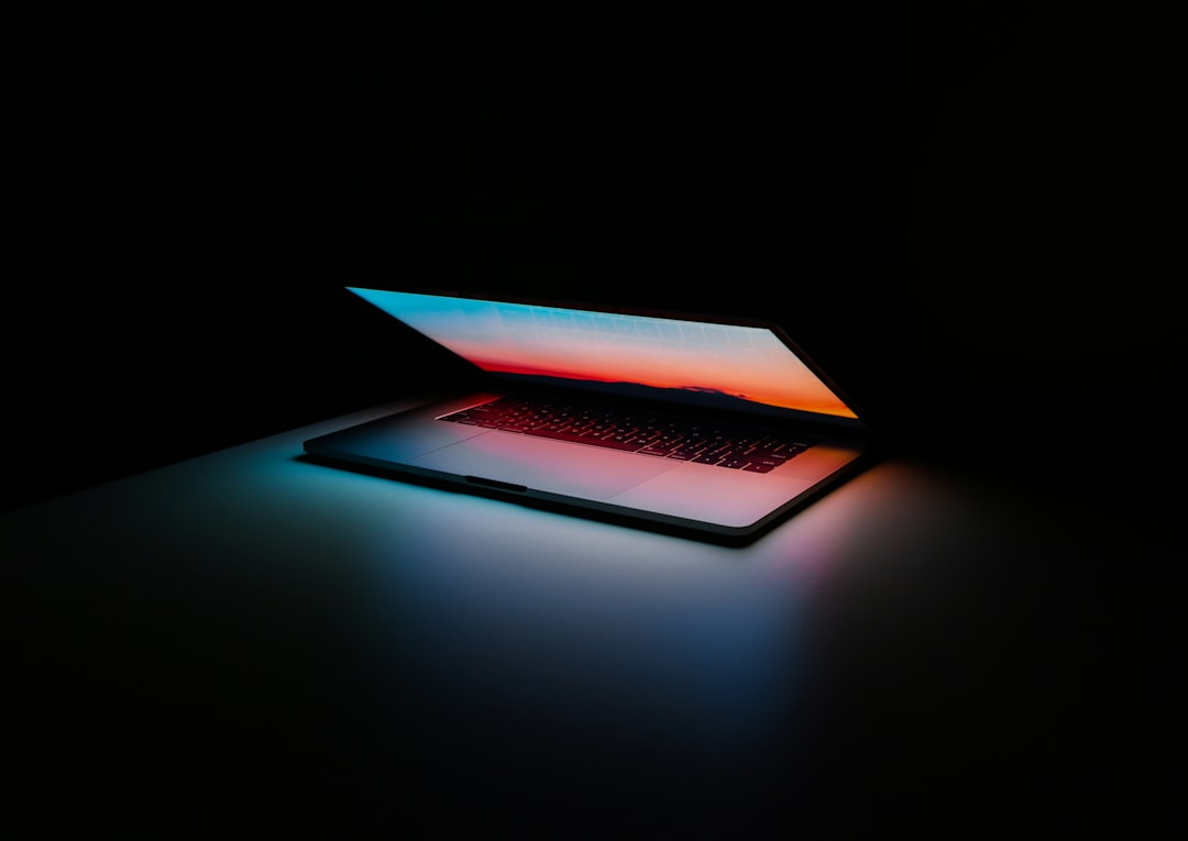 Partially open laptop with colorful screen in a dark room.