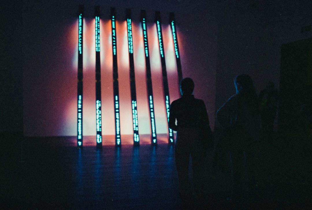 People observing a light installation in a dark room.