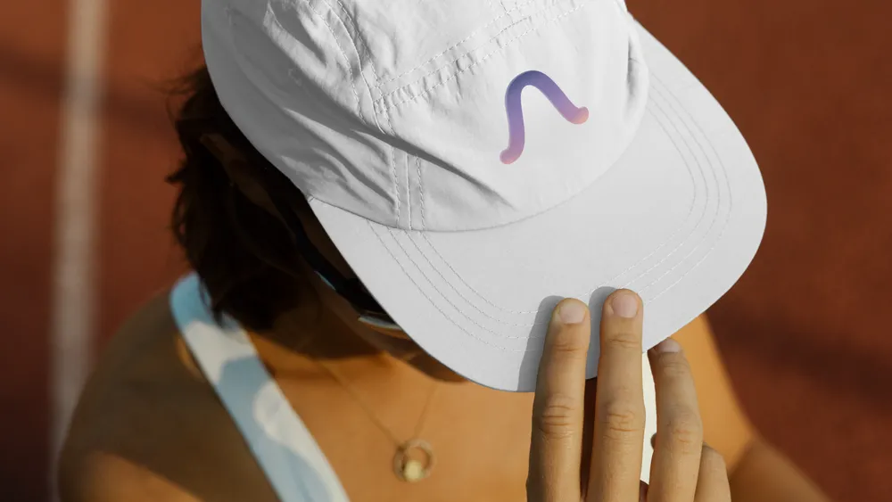 Person adjusting a white cap with a colorful logo.