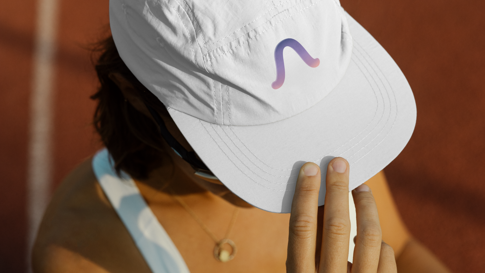 Person adjusting a white cap with a colorful logo.