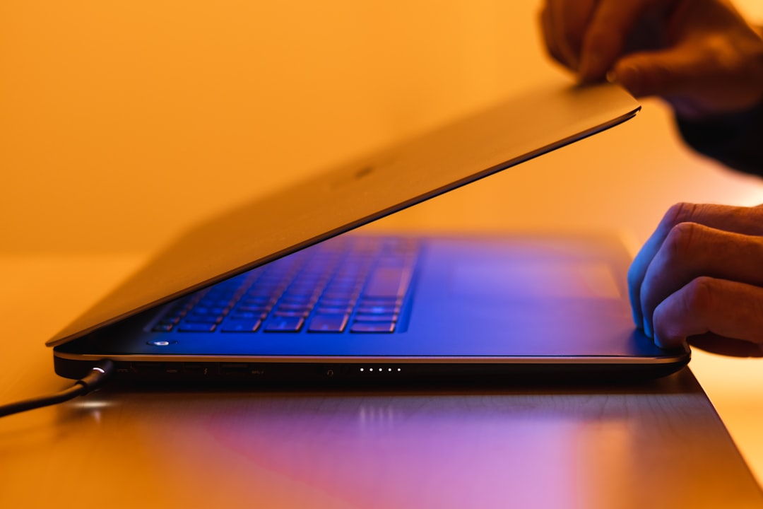 Person closing a laptop with a glowing keyboard.