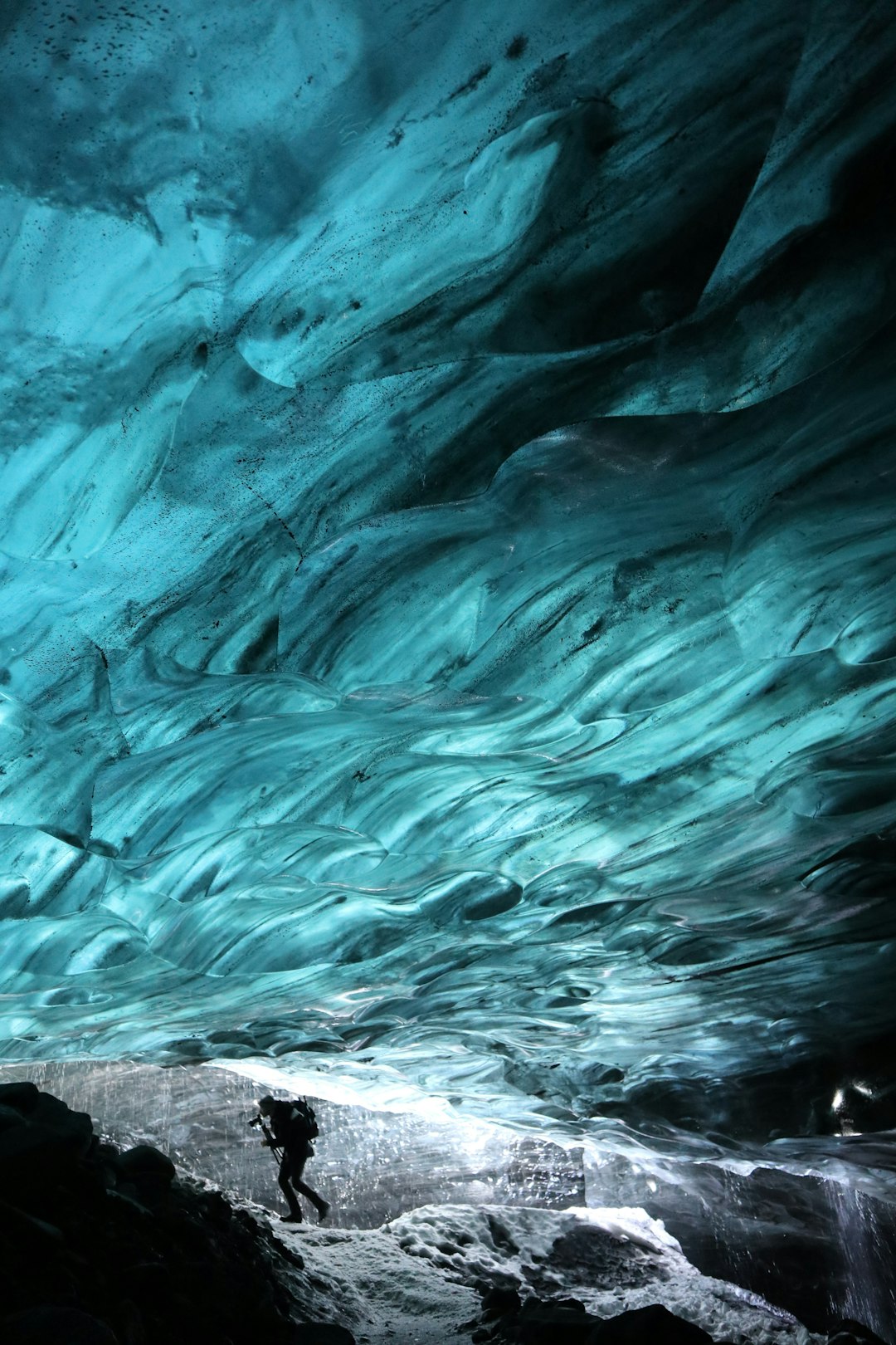Person exploring inside a blue ice cave.