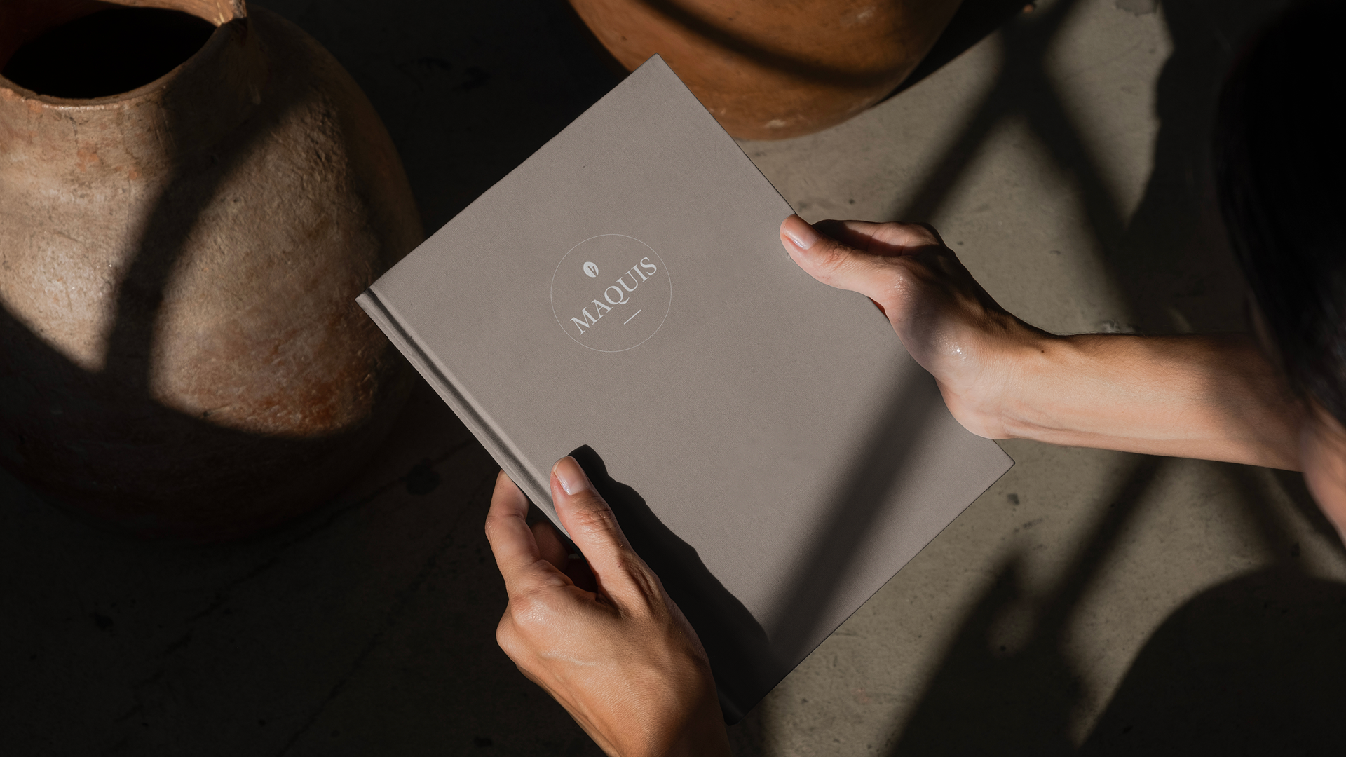 Person holding a book with the word 'MAQUIS' on the cover.