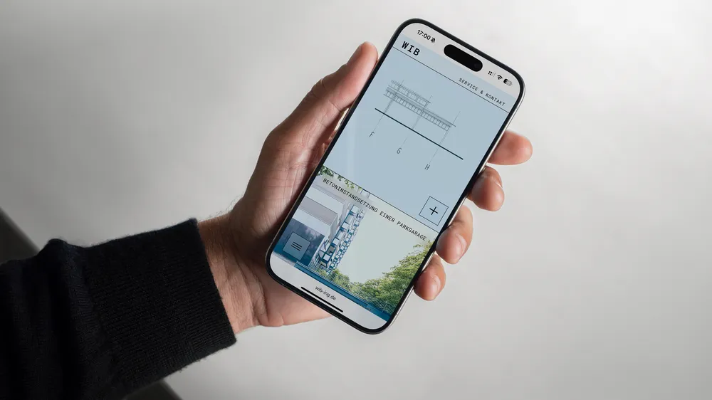 Person holding a smartphone displaying architectural drawings.