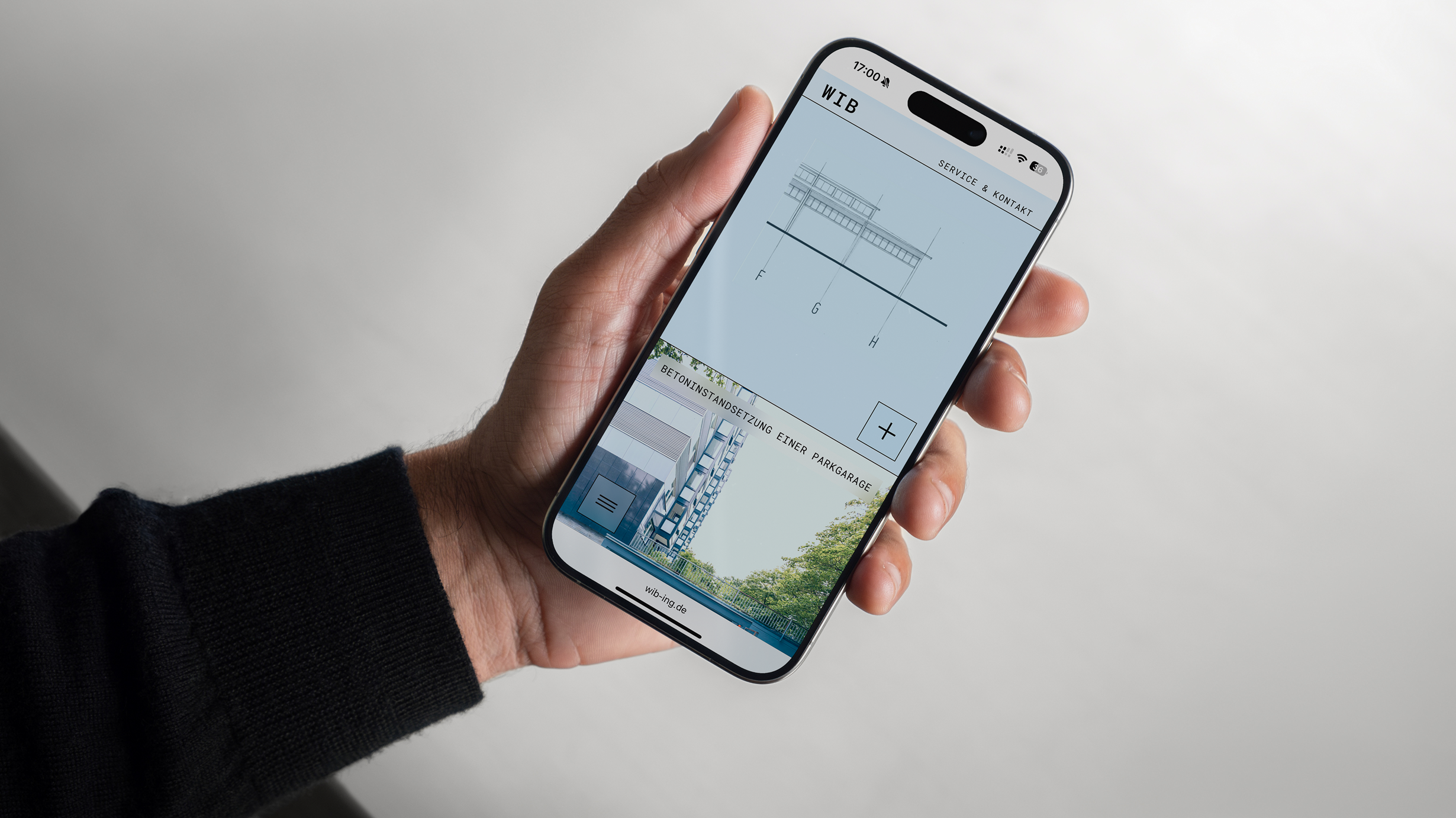 Person holding a smartphone displaying architectural drawings.