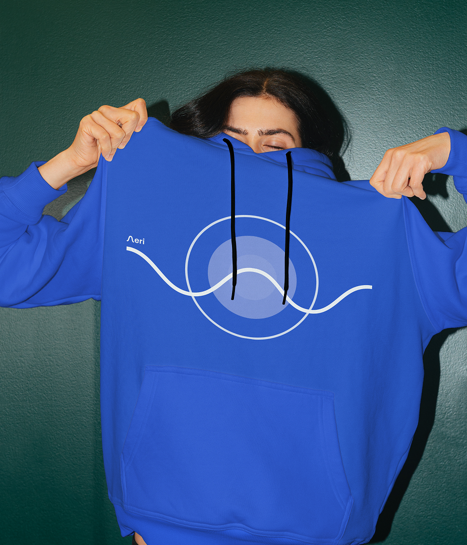 Person holding up a blue hoodie with a circular design.