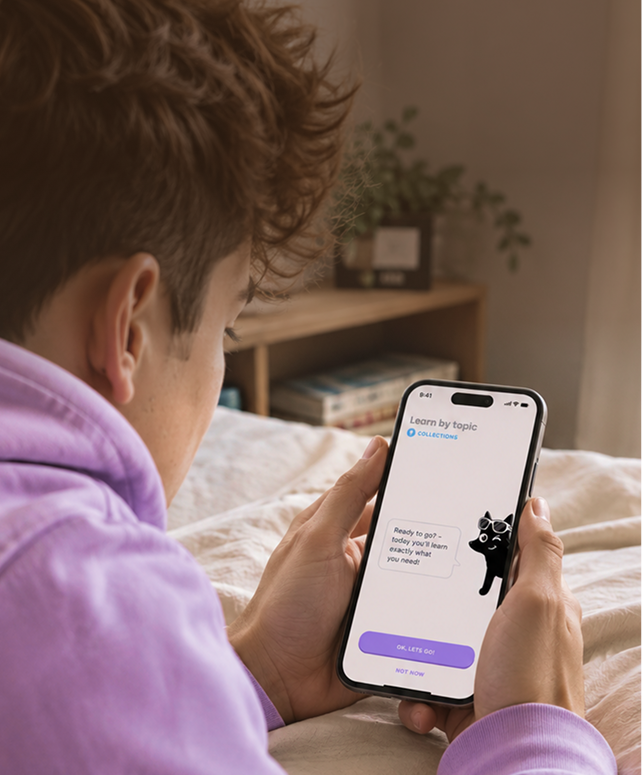 Person in a purple hoodie lying on a bed, holding a smartphone displaying a learning app interface with a cartoon cat and buttons labeled 'OK, Let's Go!' and 'Not Now'.
