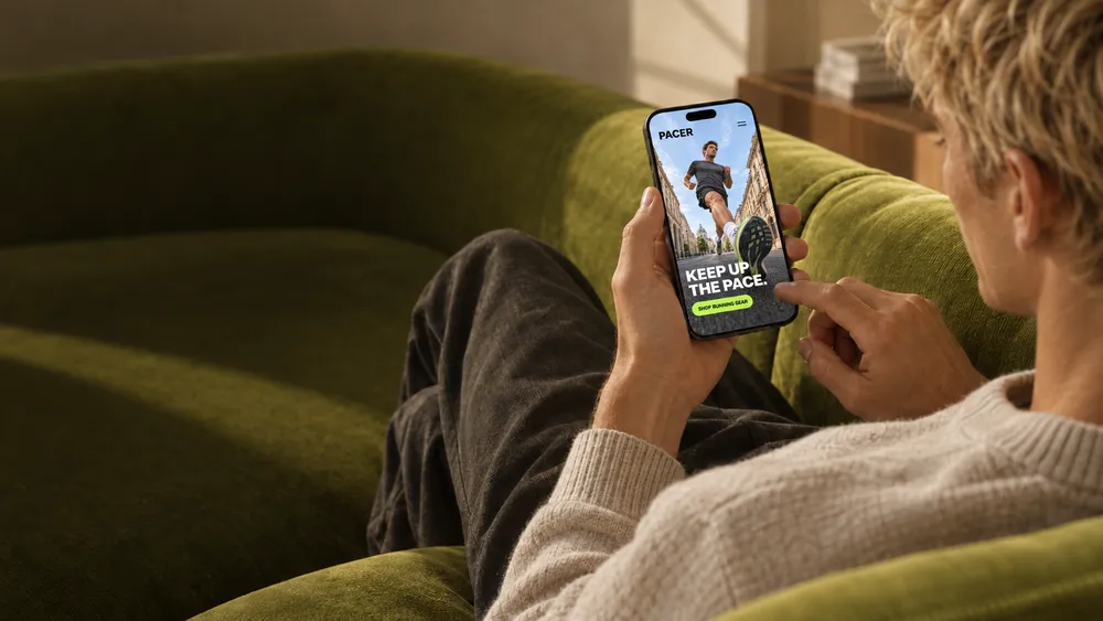 Personne assise sur un canapé vert regardant un smartphone affichant une publicité pour des équipements de course.
