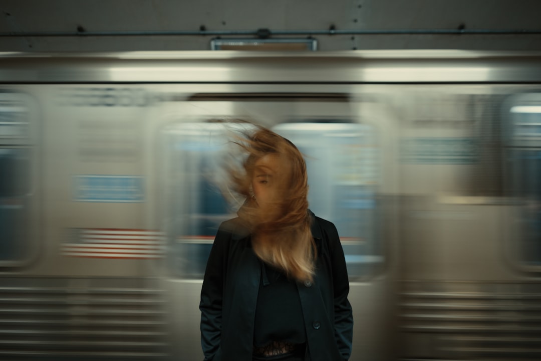 Person standing in front of a moving subway train with hair blowing.