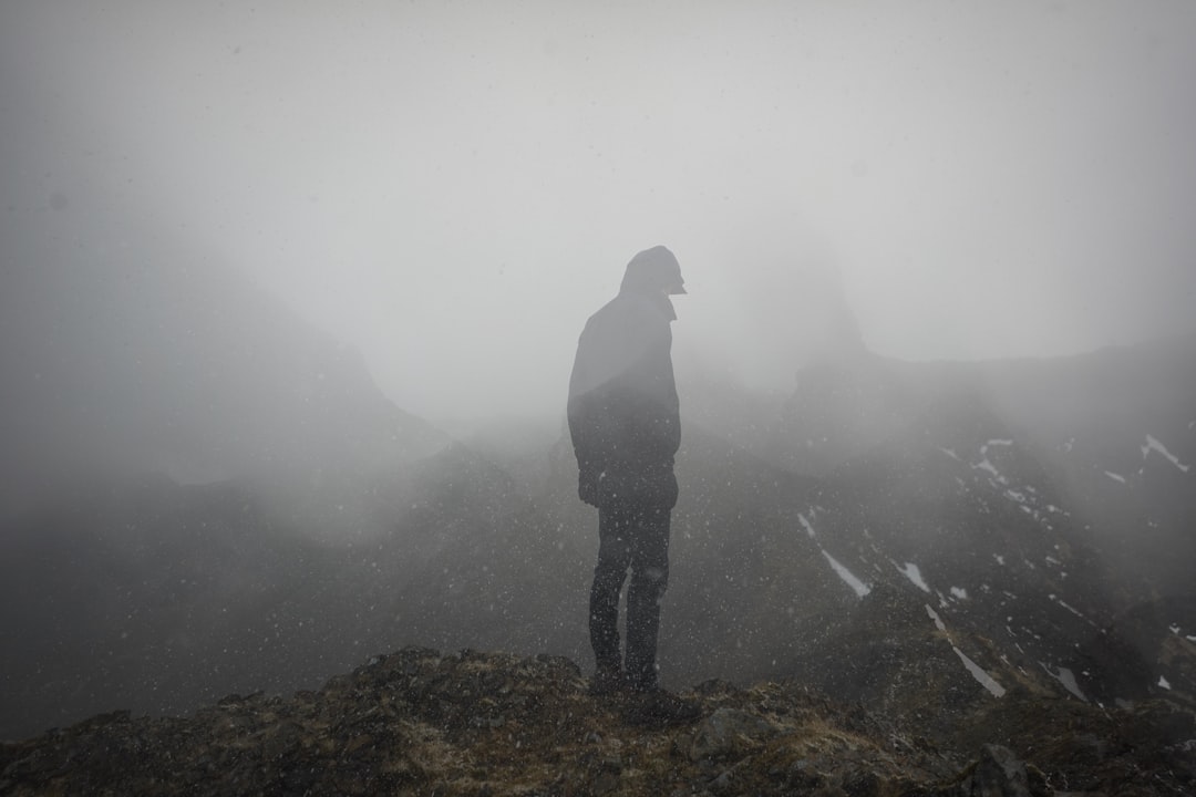 Person standing on a foggy mountain ridge.