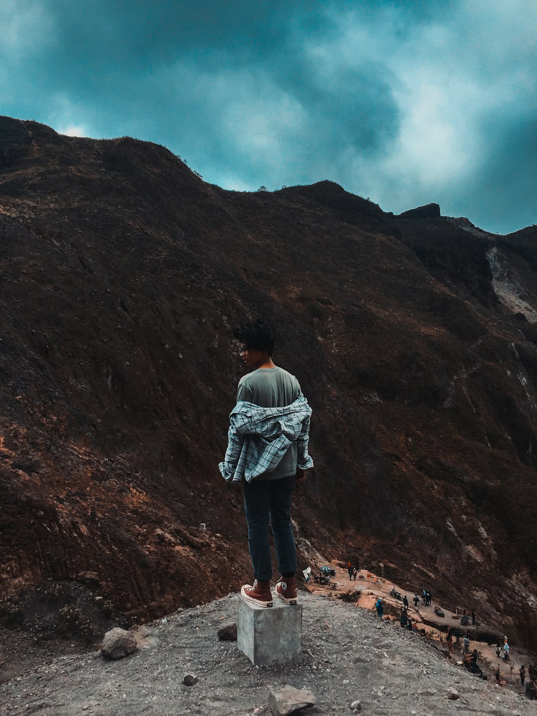 Person standing on a rock with a mountainous background.