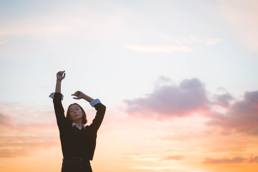 Person stretching arms under a colorful sky.