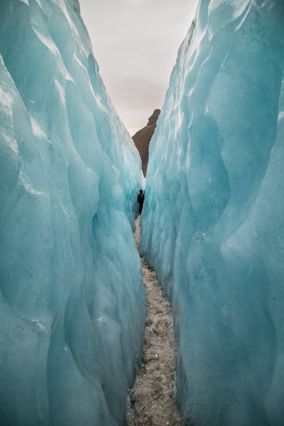 Person walking through a narrow ice canyon.